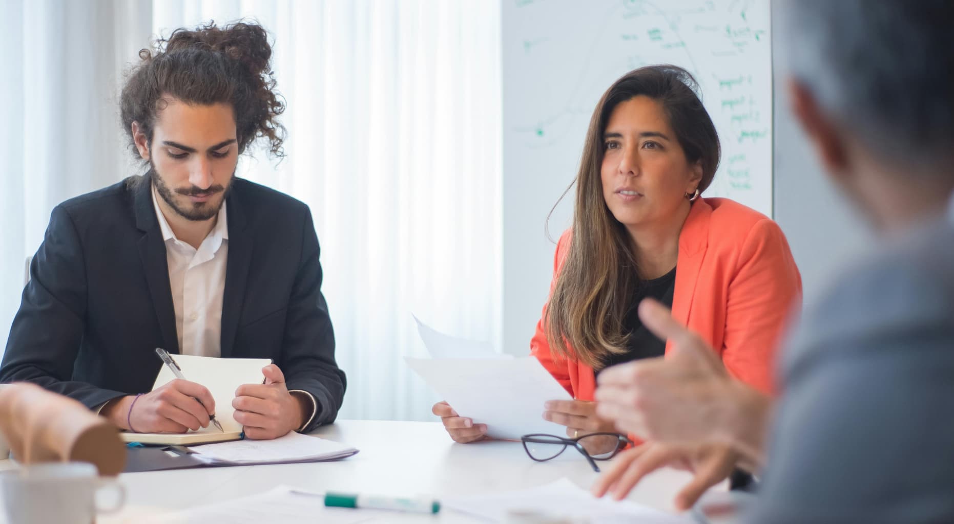 Dos colaboradores discutiendo asuntos en una junta con su jefe ejecutivo
