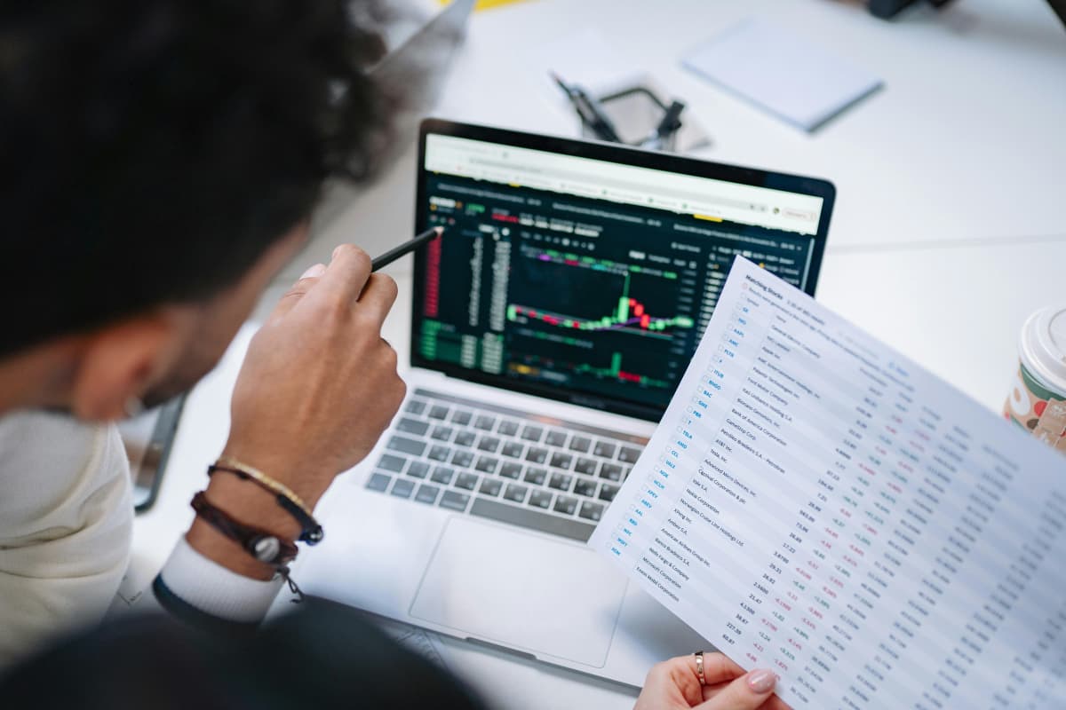 Ejecutivos revisando estadísticas en una laptop y corroborando datos impresos