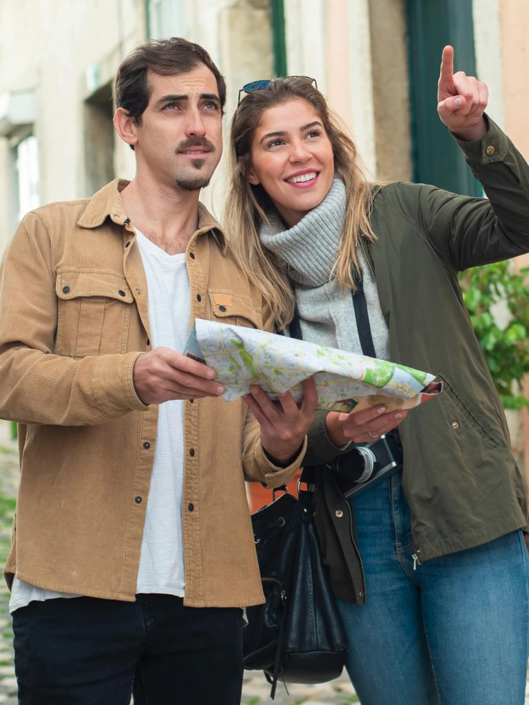 Hombre y mujer con un mapa turístico buscando lugares de interés en un viaje en el extranjero