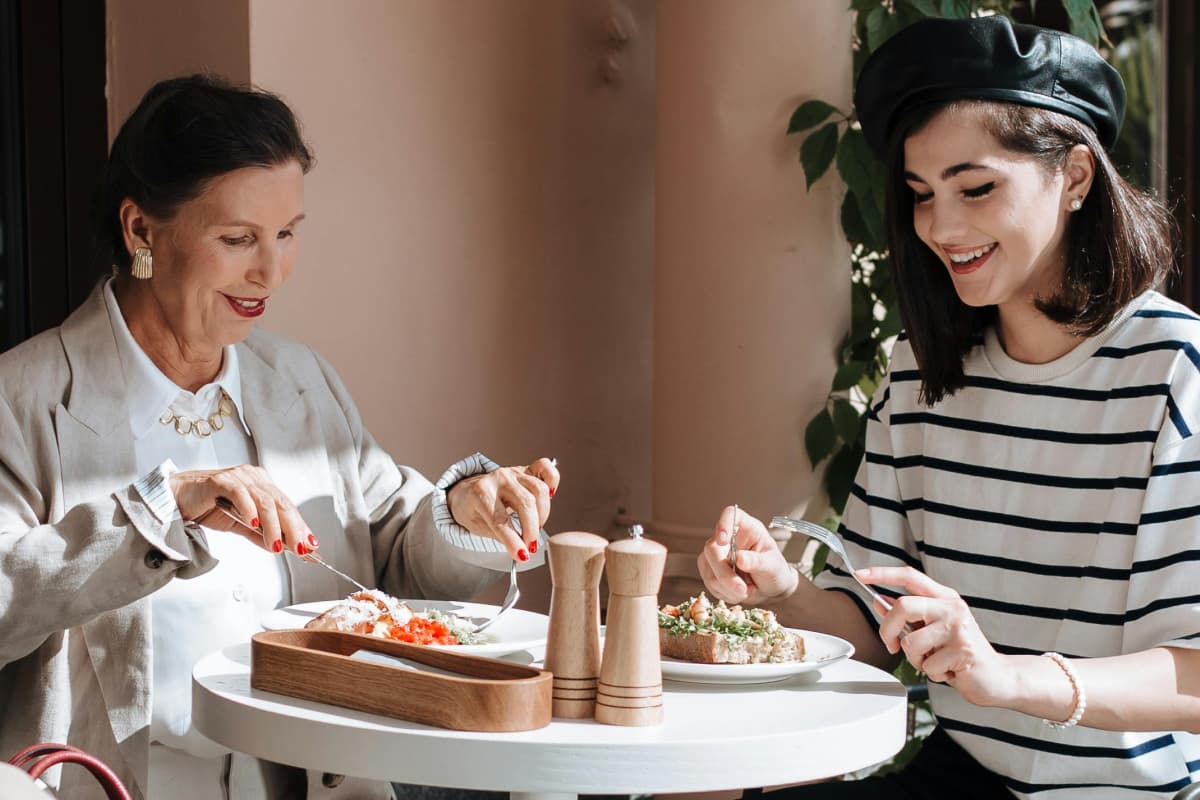 Madre e hija platicando durante una comida en un la parte exterior de un restaurante
