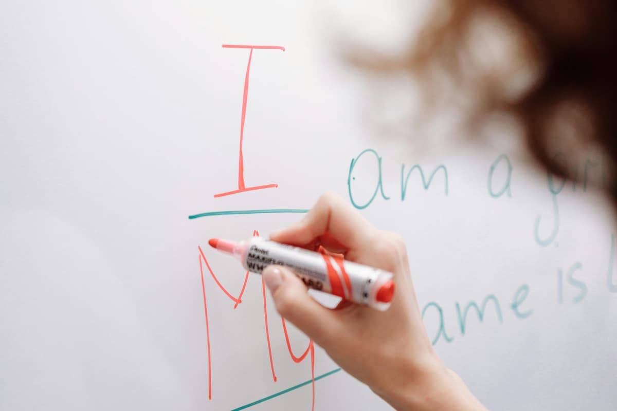 Profesora de inglés mostrando estructuras gramaticales en un pizarrón